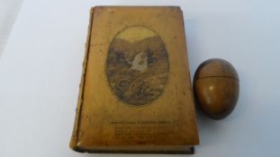 A TREEN WARE COTTON REEL HOLDER IN THE FORM OF AN EGG TOGETHER WITH A WOODEN CARVED BOOK `THE