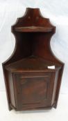 A SMALL MAHOGANY EFFECT CORNER CABINET WITH CUPBOARD BELOW AND ORNAMENT SHELF TO THE TOP