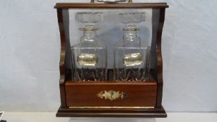 A MODERN MAHOGANY TANTALUS CONTAINING TWO DECANTERS WITH BIRMINGHAM HALLMARKED SOLID SILVER BRANDY