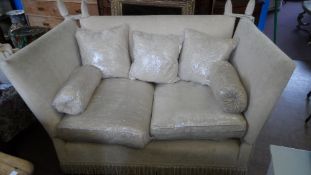 A TWO SEATER KNOWLE STYLE SETTEE COVERED IN A CREAM FABRIC