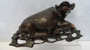 AN ANTIQUE HARDWOOD CHINESE FIGURE OF AN OX, THE BODY INLAID WITH SILVER STRANDS AND HAVING GLASS