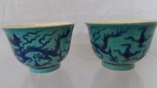 A PAIR OF BLUE AND TURQUOISE TEA BOWLS DEPICTING DRAGONS IN FLIGHT AMONGST THE CLOUDS. 5 X 6 cms