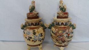 A PAIR OF JAPANESE SATSUMA EARTHENWARE JARS ON THREE FEET. PAINTED SAMURAI WARRIORS IN A LANDSCAPE