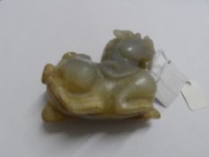 A WHITE CHINESE HARD STONE CARVING OF A DRAGON ON HIS HAUNCHES, APPROX. 8 X 6 CM