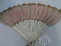 A CIRCA 1900 HAND PAINTED SILK AND BONE STICK FAN. THE PETAL SHAPED BLADES DEPICTING FLOWERS 39 X 26
