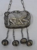 AN ANTIQUE SILVER METAL ORIENTAL SHAPED BOX ON A CHAIN WITH FOUR SUSPENDED BELLS - THE BOX DEPICTING