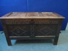 A CIRCA 17th CENTURY CARVED OAK COFFER STANDING ON STRAIGHT FEET - THE CHEST HAVING PANELLED TOP AND