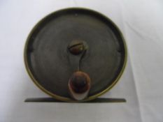 A SMALL ANTIQUE BRASS FLY FISHING REEL WITH IMPRESSED TRADE MARK OF A STAG, APPROX. 2.5" DIAMETER,