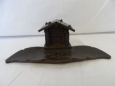 A BLACK FOREST STYLE INKWELL IN THE FORM OF A LEAF WITH A COTTAGE, THE COTTAGE CONTAINS THE GLASS
