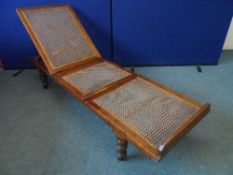 AN ANTIQUE TEAK AND RATTAN DAY BED WITH ADJUSTABLE BACK ON TURNED FEET WITH CASTORS - AN IVORINE