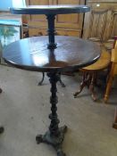 A WOODEN TWO TIER CIRCULAR PUB TABLE ON AN ORNATE CAST IRON CENTRE COLUMN WITH THREE SPLAYED FEET,