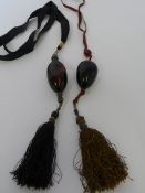 TWO ANTIQUE ORIENTAL AMBER LOZENGE NECKLACES ON A SILK CORD WITH SILVER WIRE TASSEL TO BOTTOM