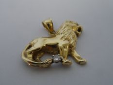 A 14 K YELLOW GOLD HALLMARKED PENDANT DEPICTING A LION. THE LION IS SET WITH AN EMERALD EYE AND A