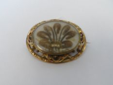 AN EDWARDIAN OVAL MOURNING BROOCH WITH GLASS CAMEO FRONT CONTAINING GOLD WIRE SEED PEARLS AND HAIR