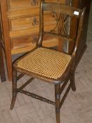 AN EDWARDIAN RATTAN SEATED BEDROOM CHAIR HAVING X SHAPED DECORATION TO THE BACK ON TURNED FRONT LEGS