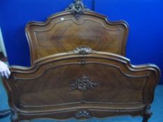 A FRENCH WALNUT CARVED BEDSTEAD,THE HEAD BOARD HAVING FLORAL FINIAL TO THE TOP, VENEERED PANEL TO
