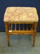 A SATIN WOOD PIANO STOOL ON TURNED LEGS AND STRETCHERS WITH SLATTED SHELF UNDER AND HAVING SPINDLE