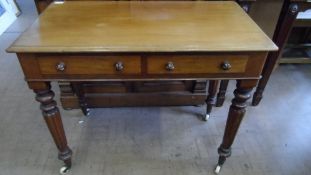 A VICTORIAN MAHOGANY TWO DRAWER WRITING DESK WITH TURNED LEGS AND HANDLES AND PORCELAIN CASTORS,