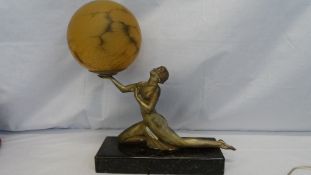 AN ART NOUVEAU METAL LAMP IN THE FORM OF A NAKED LADY HOLDING A GLOBE, THE FIGURE KNEELING POSING ON