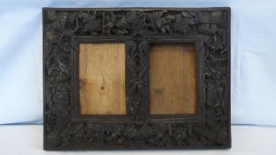 AN ANTIQUE CARVED CHINESE WOODEN DOUBLE PICTURE FRAME DEPICTING DRAGONS ENTWINED TO CENTRE WITH