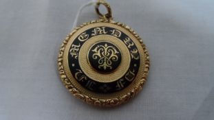 AN EDWARDIAN GOLD AND ENAMEL MOURNING LOCKET, THE ENGINE TURNED LOCKET HAVING INITIALS WITHIN