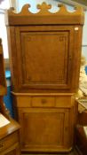 A LARGE ANTIQUE PINE CORNER CUPBOARD HAVING A CARVED CORNICE TO THE TOP AND DECORATION TO THE DOORS,