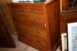 AN EDWARDIAN OAK CHEST OF DRAWERS HAVING TWO SHORT AND THREE LONG DRAWERS, THE CHEST BEING ON A