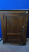 A VICTORIAN MAHOGANY CORNER CUPBOARD HAVING A PANELLED DOOR AND SHAPED SHELVES TO THE INTERIOR,