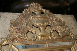 AN ORNATE ROCOCO STYLE GILT MIRROR, THE MIRROR HAVING OVAL GILT PANEL BORDERED WITH LEAVES,