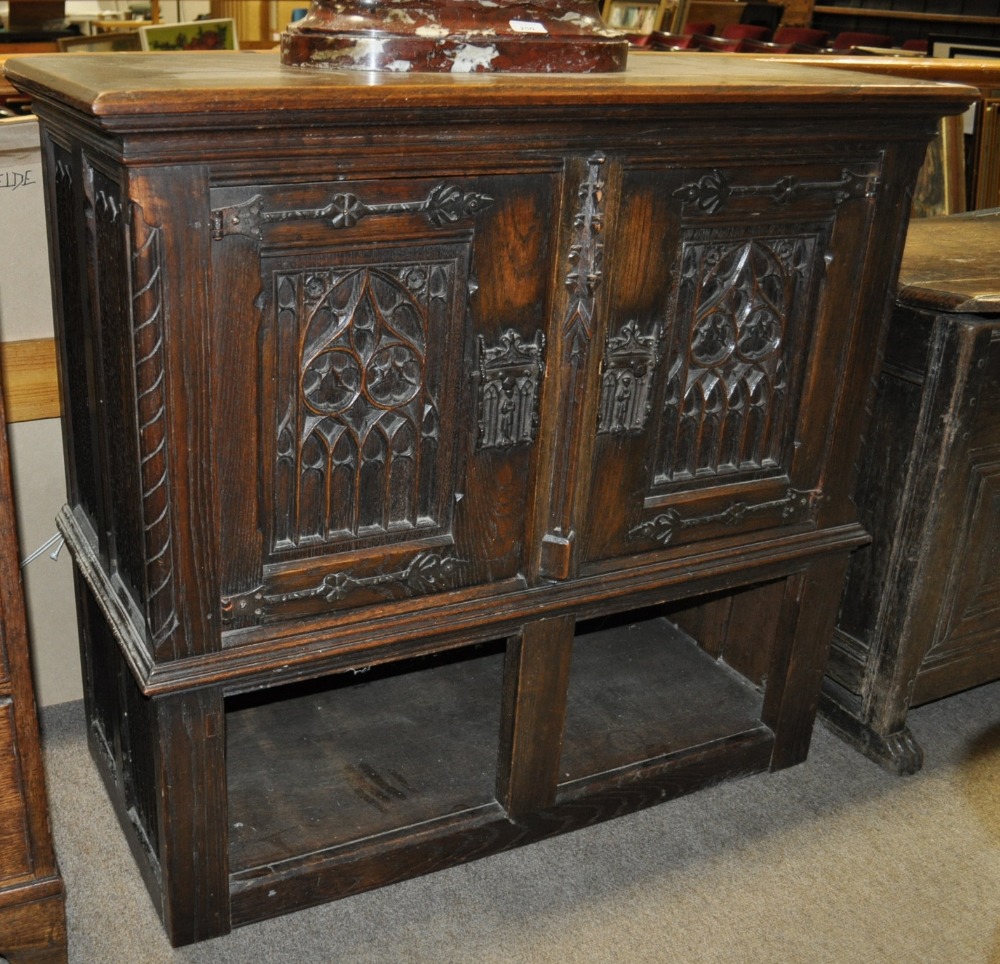 A 17th century style oak cabinet with Gothic carved panelled doors and shelf under, width 38.5".