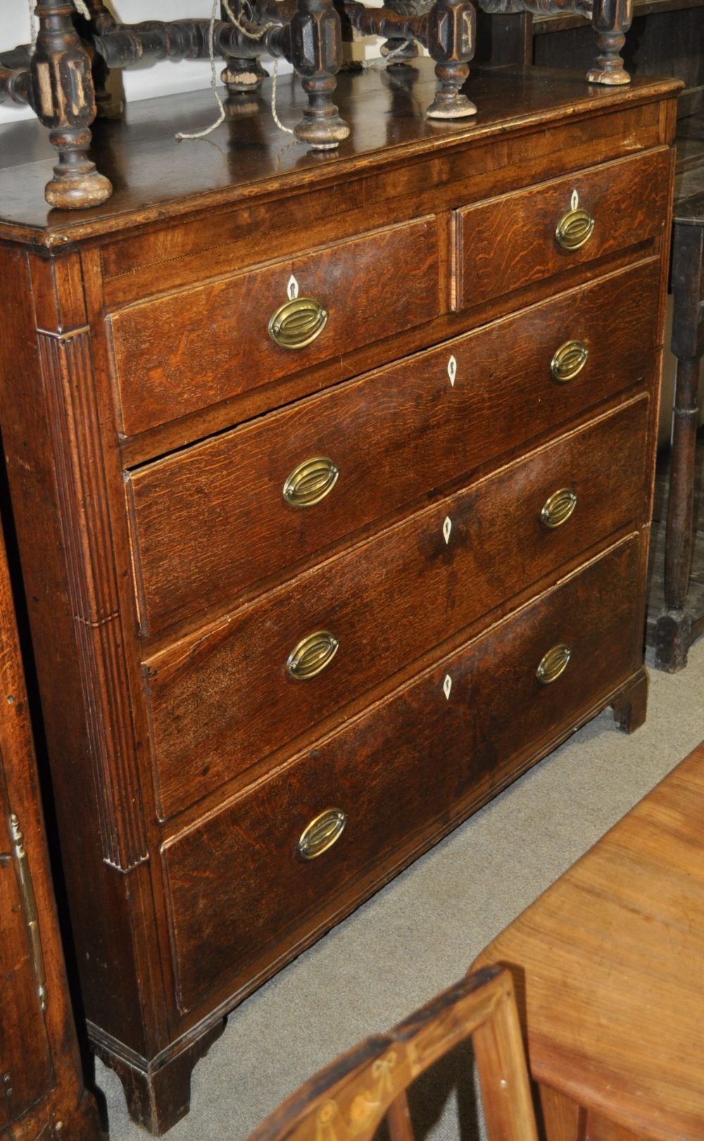 A large George III oak chest of 2 short and 3 long drawers, having ebony banding raised on bracket