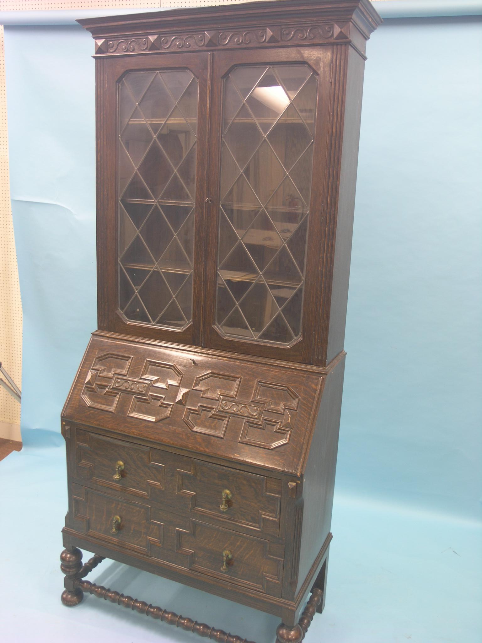 An early 20th century solid, dark oak bureau bookcase, pair of leaded glazed doors enclosing three