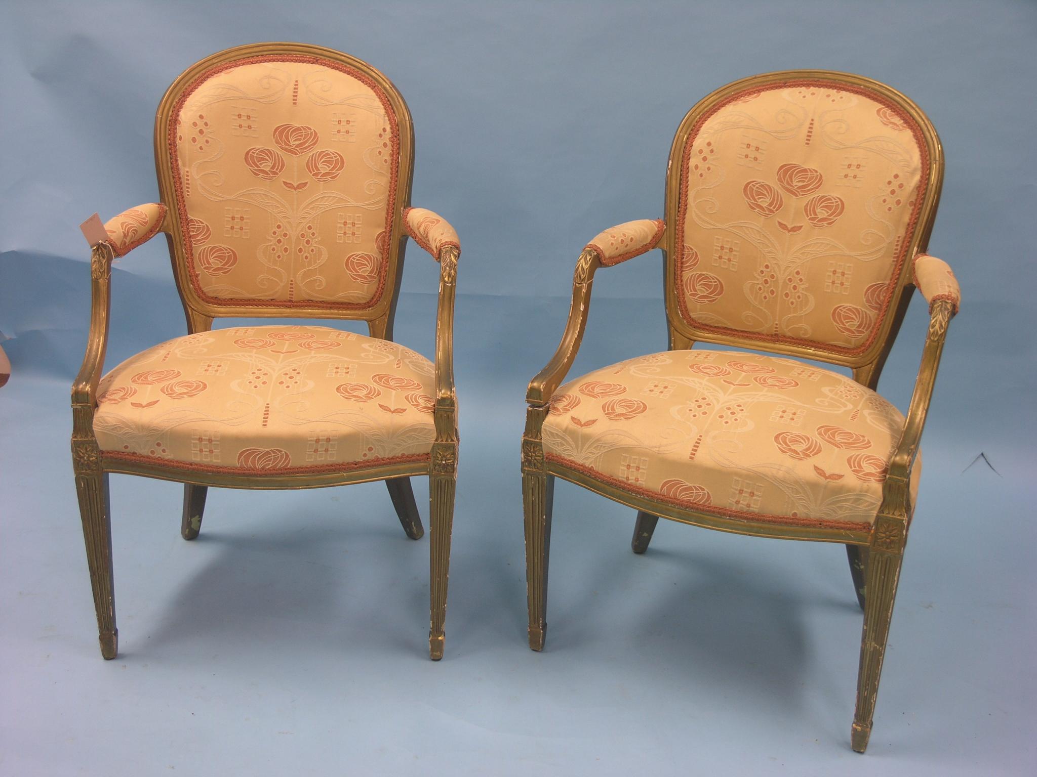 A pair of Louis XVI-style giltwood elbow chairs, upholstered in a gold floral fabric