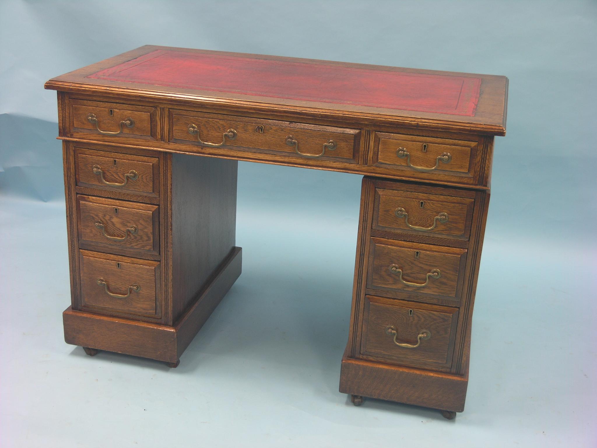 An early 20th century oak pedestal desk, inset vinyl top above three frieze drawers, three further