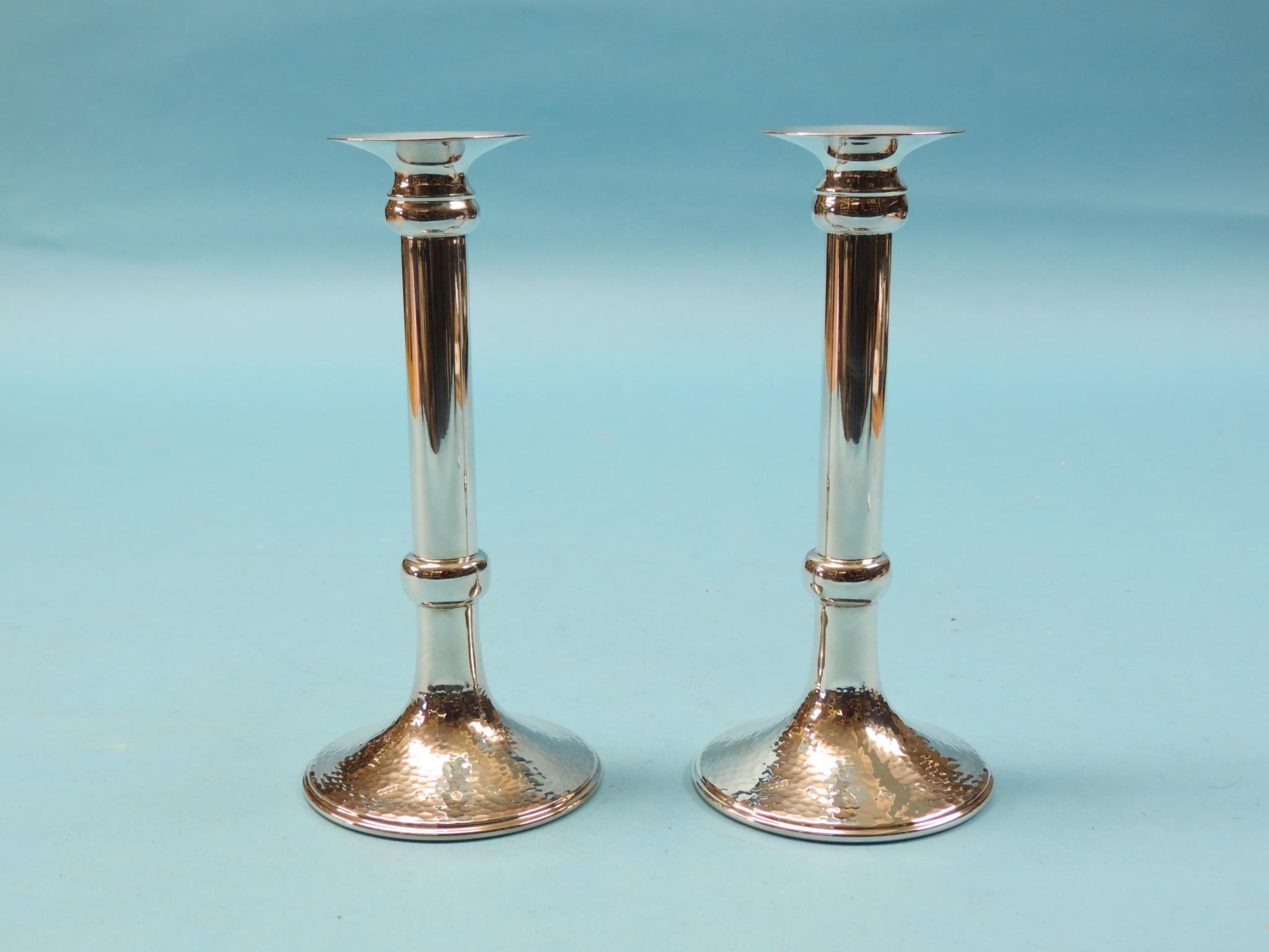 A pair of modern silver candlesticks, cylindrical stems and hammered circular bases, approx. 17oz.