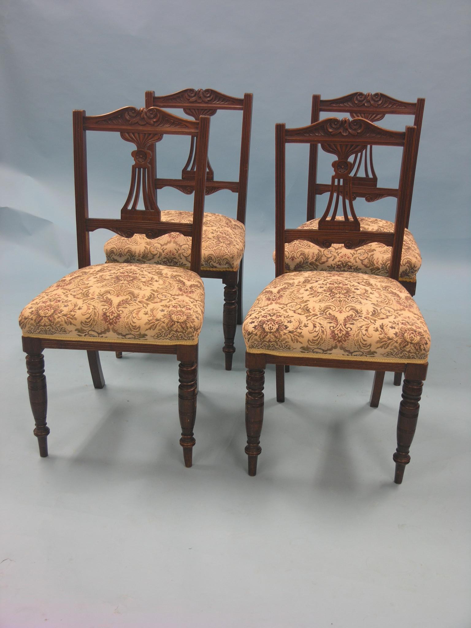 A set of four Edwardian walnut dining chairs, backs with carved detail, machine tapestry seats, on