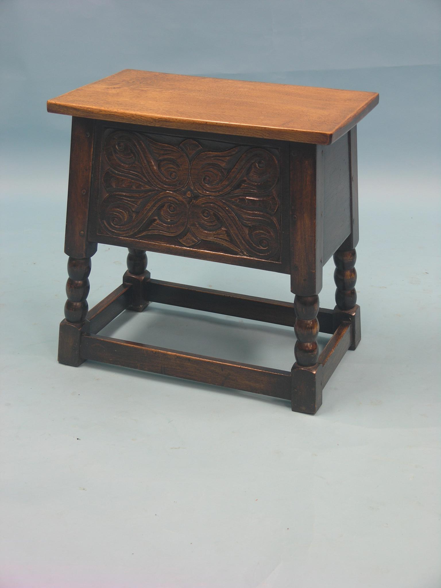 A Reprodux oak box-stool, frontage carved with leaf scrolls on ball-turned legs, 1ft. 7in. £30-40