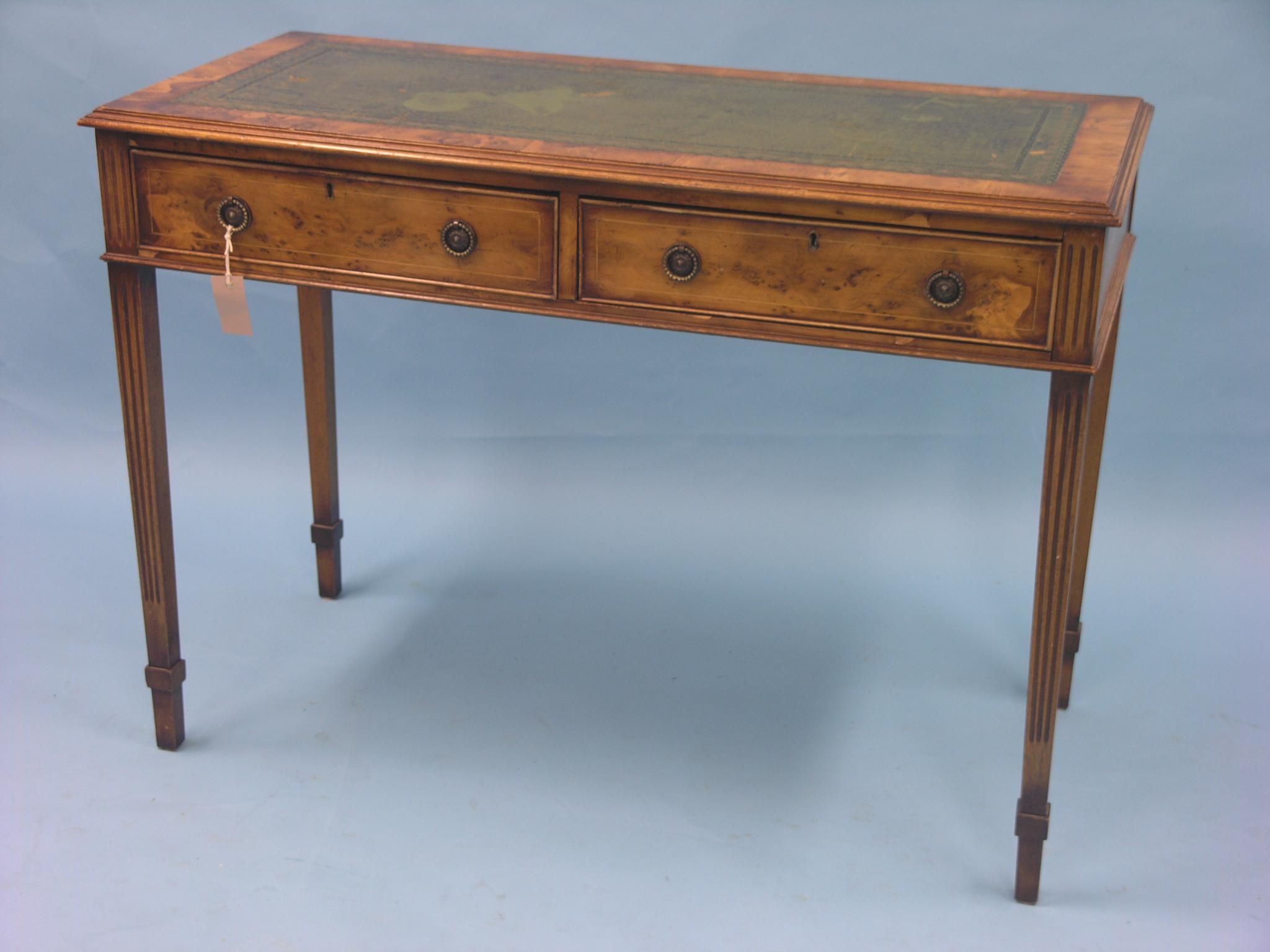 A reproduction yew-veneered writing table, inset gilt-tooled leather top above two frieze drawers,