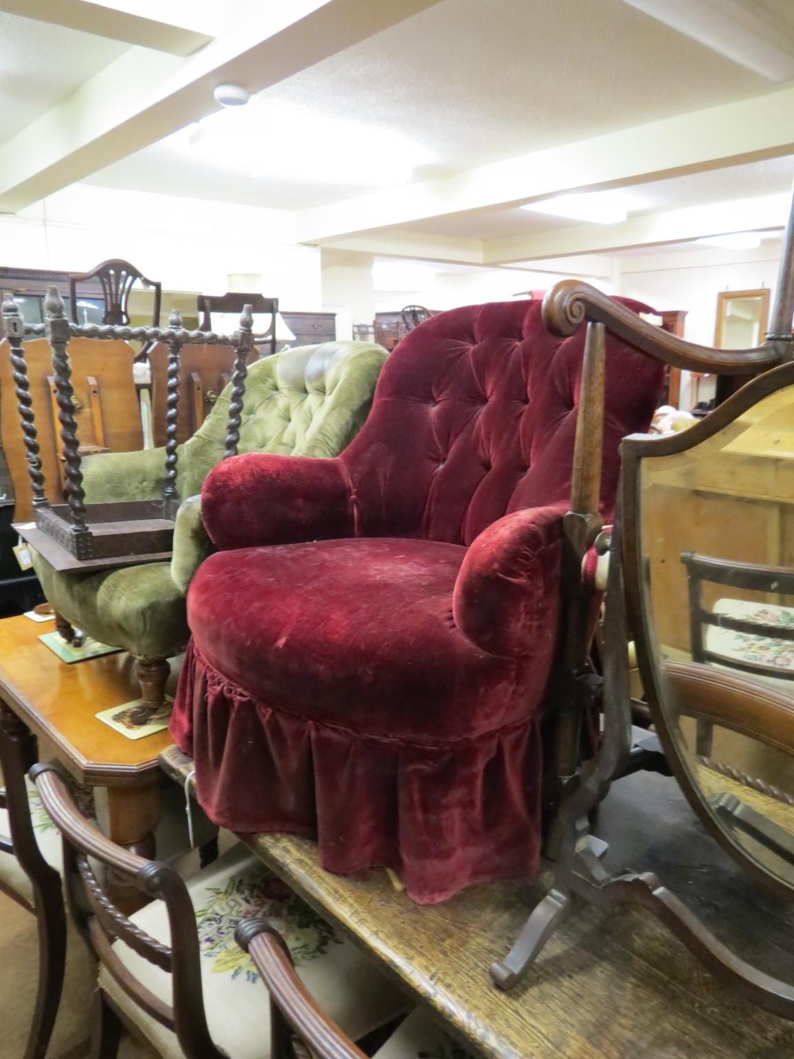 A Victorian spoon-back armchair, on front turned legs with casters, maroon upholstery as viewed