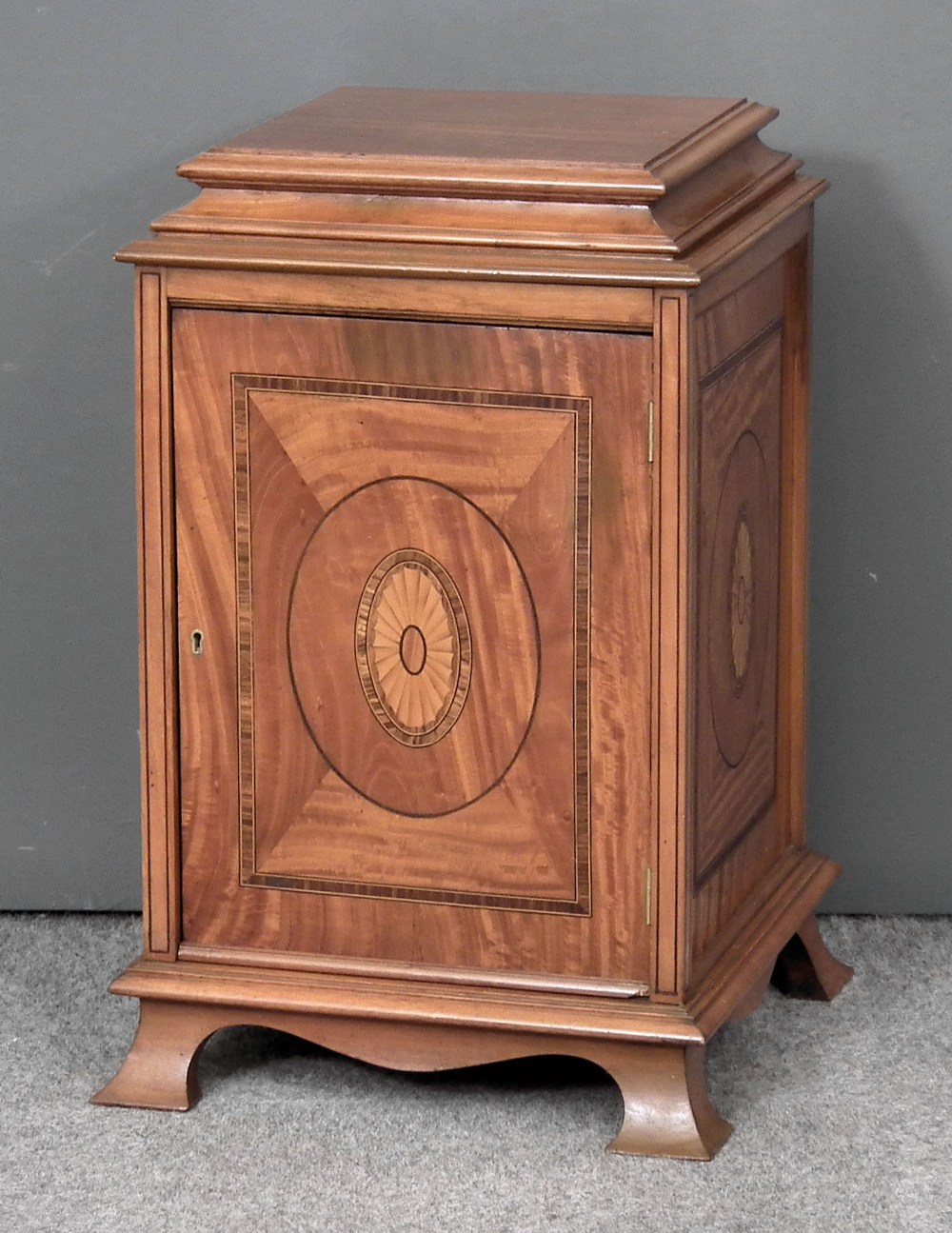 An Edwardian panelled satinwood square pedestal cupboard inlaid to each side with oval paterae and