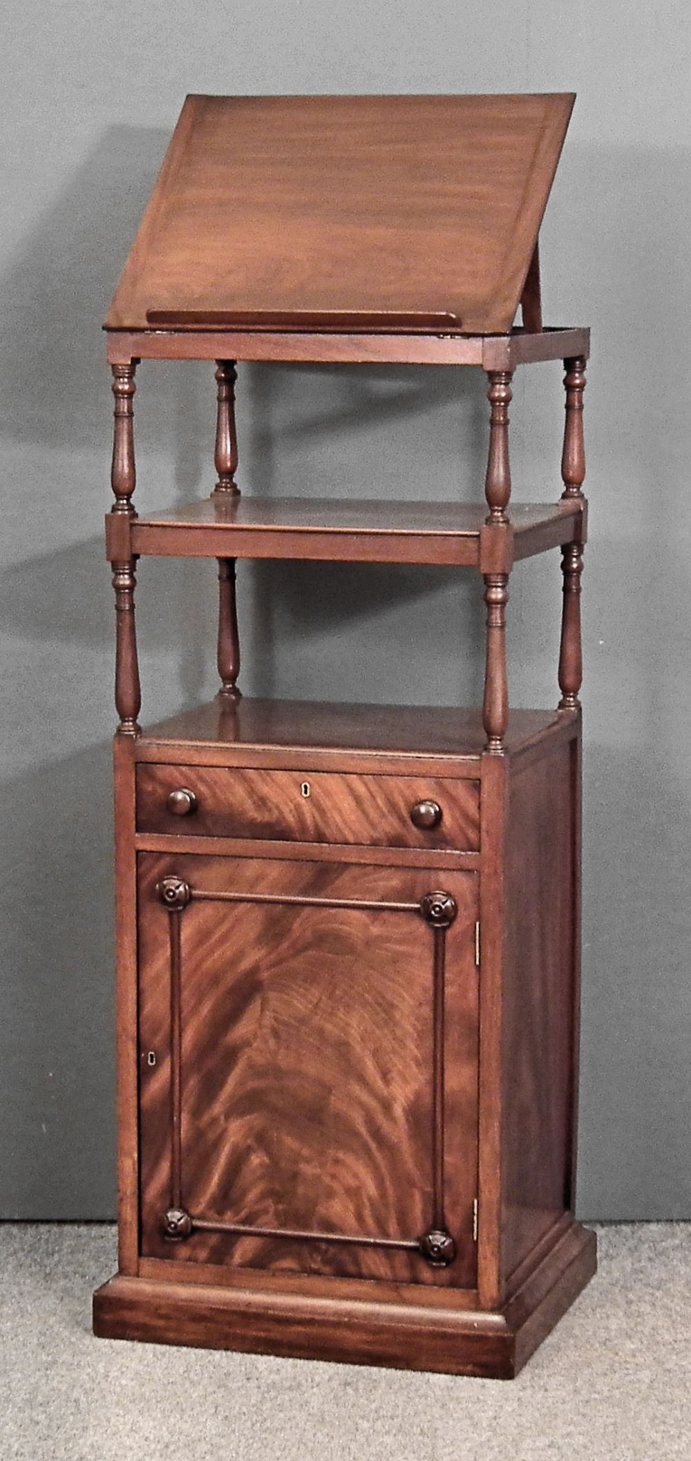 A late Georgian mahogany three tier whatnot, the top with adjustable reading slope, on slender