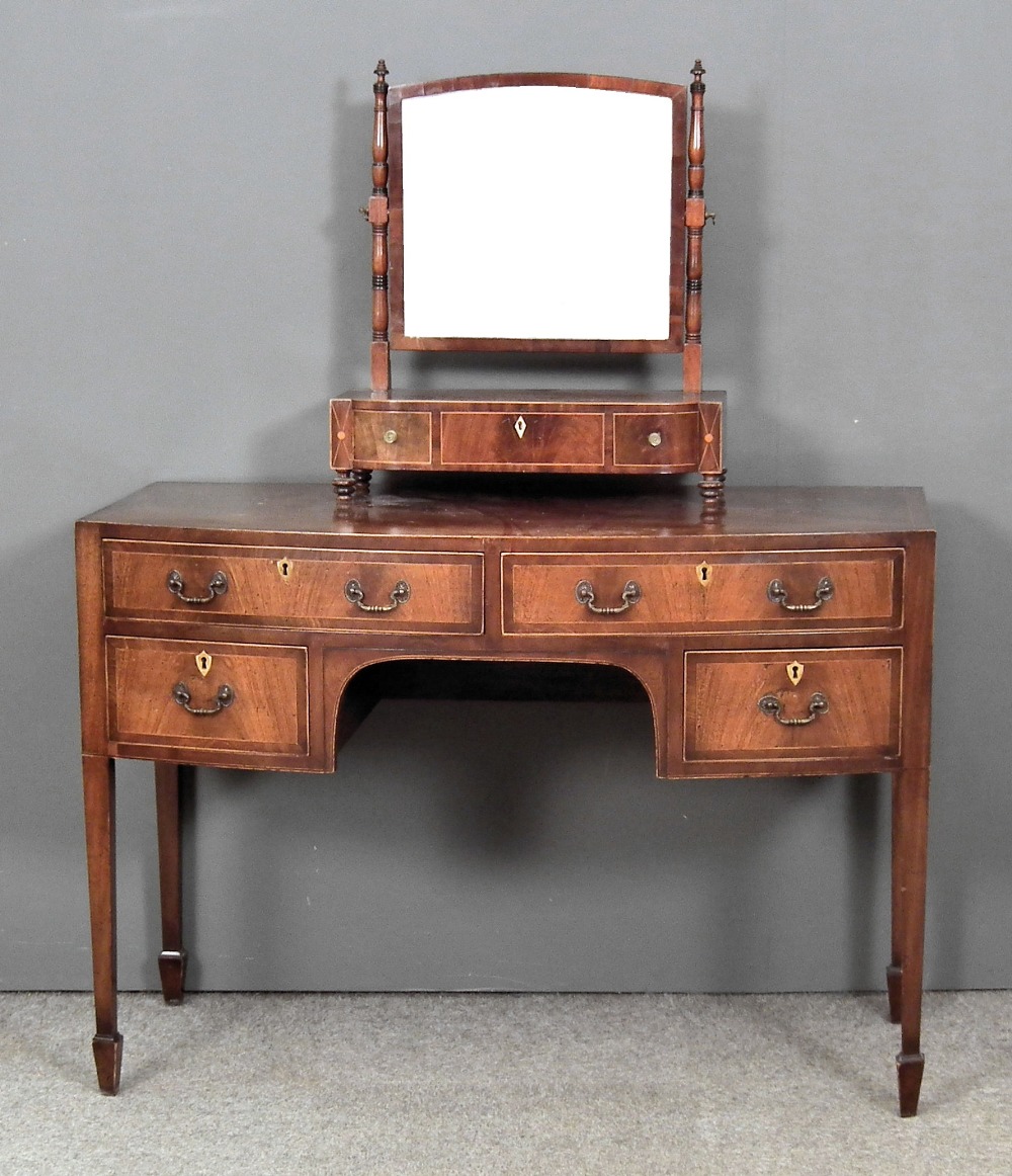 A mahogany bow-front dressing table of Georgian design with crossbanded top, fitted four drawers, on