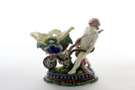 An early 20th Century Continental Maiolica Centrepiece, formed as a cherub pushing a cart supporting