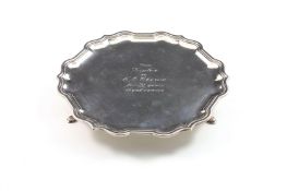 A silver salver, hallmarked Sheffield 1967, with pie crust rim and supported on three feet. With