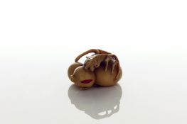 A Japanese carved ivory netsuke of a pomegranate, with two smaller fruits beside, Meiji period