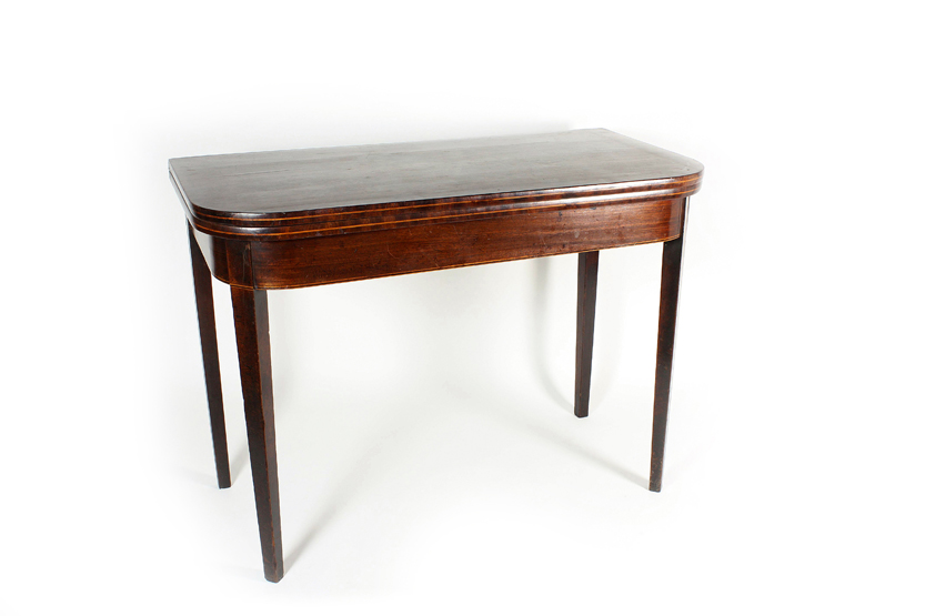 A late George III mahogany card table, with rounded front and boxwood stringing, raised on tapered