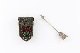 An Art Deco dress clip set with marquasite and red and green carved stones, together with an arrow