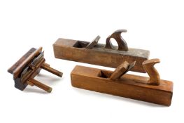 A small collection of wood working tools, comprising a wooden jack plane, a trying plane and a