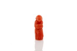 A small carved coral charm, formed as a monk kneeling and holding a prayer book, 2.3cm high