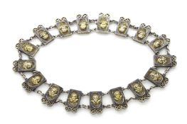 A Continental white metal collar necklace, with seventeen tablets set with gilded winged cherubs,